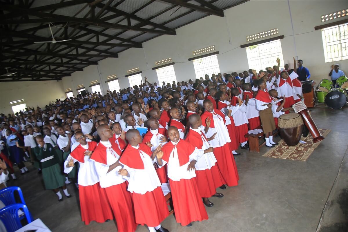 The choir in red and white and the students fill the school hall for the thanksgiving Mass