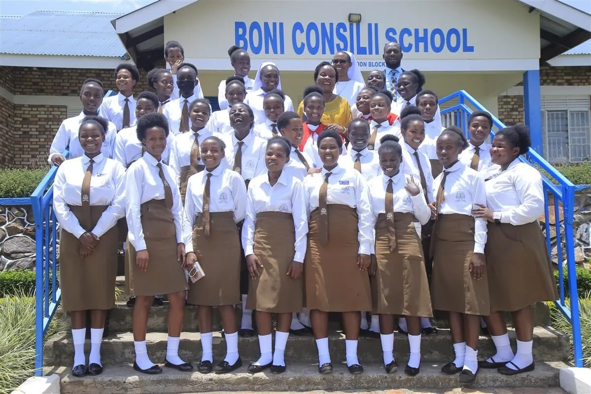 A level students in white shirts and brown skirts on the steps of the school building